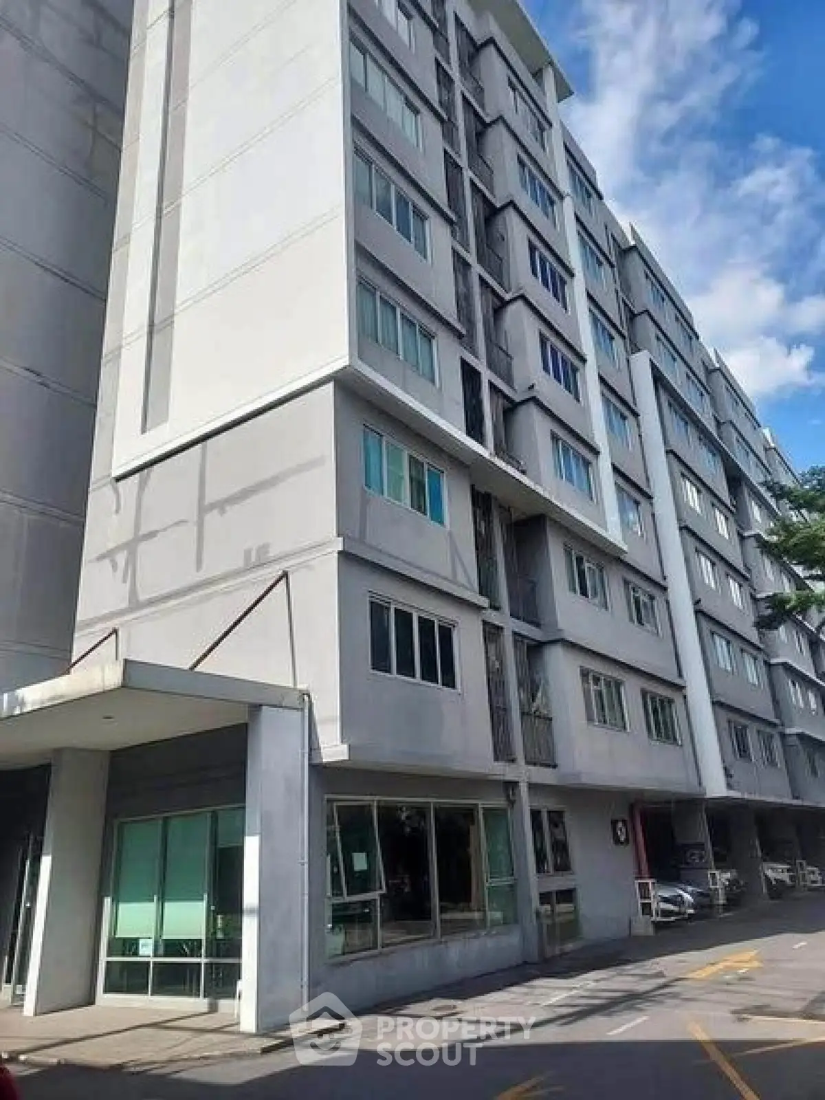 Modern multi-story residential building with large windows and street view.
