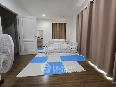 Spacious bedroom with crib and play area, featuring wooden flooring and soft lighting.