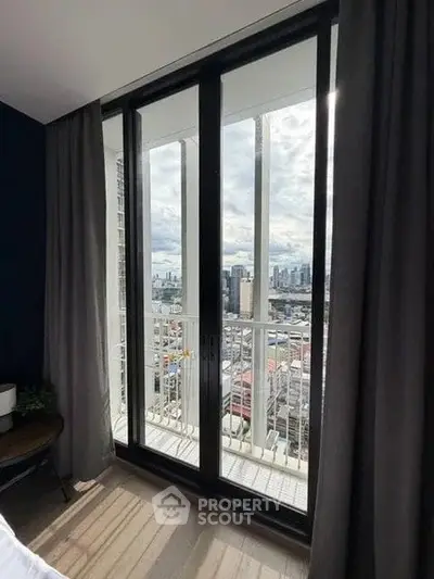 Stunning city view from modern apartment balcony with floor-to-ceiling windows.