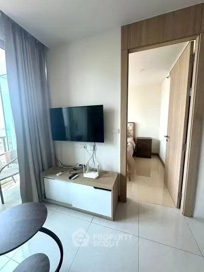 Modern apartment interior with sleek TV setup and glimpse of cozy bedroom