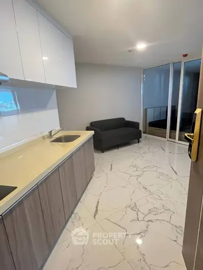 Modern kitchen with sleek cabinets and marble flooring, featuring a cozy sofa and mirrored closet.