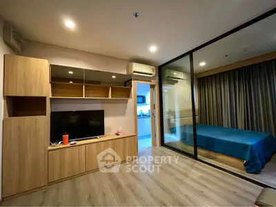 Modern apartment interior with open living room and bedroom, featuring sleek wooden furniture and glass partition.