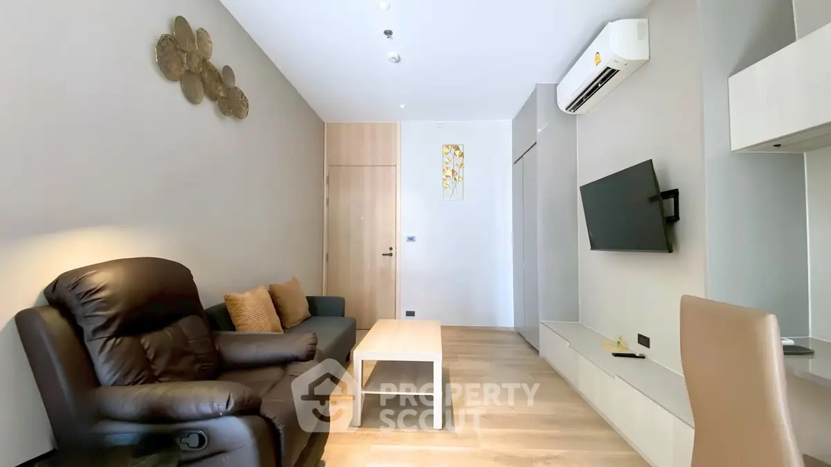 Modern living room with sleek design, featuring a leather sofa, wall-mounted TV, and air conditioning.