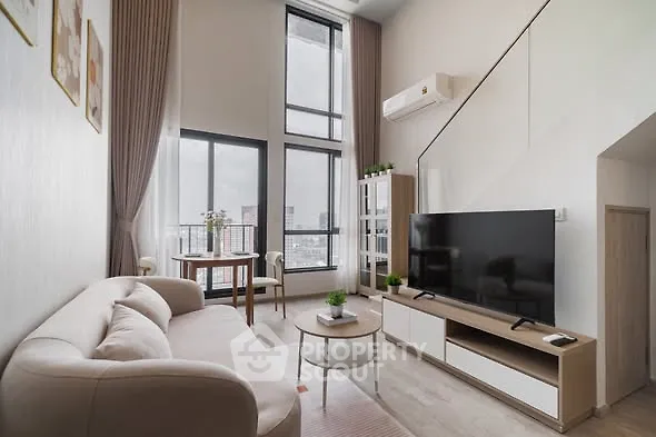 Modern living room with high ceilings and large windows offering city views.