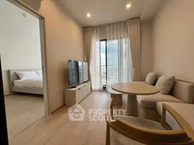 Modern living room with natural light and cozy furniture, open to a bedroom with a view.