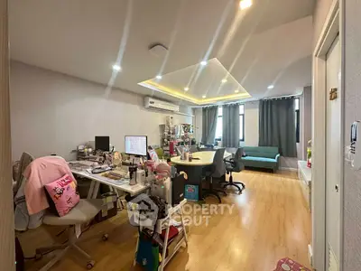 Spacious home office with modern lighting and cozy seating area, perfect for productivity and relaxation.