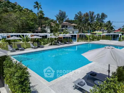 Luxurious outdoor pool area with sun loungers and umbrellas, surrounded by lush greenery and modern architecture.