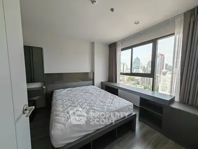 Modern bedroom with city view, featuring sleek furniture and large windows for natural light.