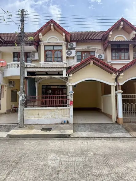 Charming townhouse exterior with tiled roof and spacious driveway in a serene neighborhood.