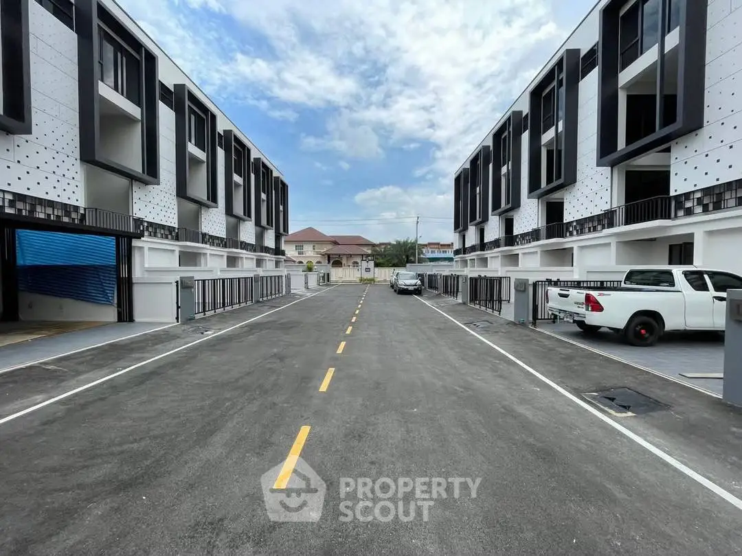 Modern townhouse complex with sleek design and ample parking space, showcasing contemporary urban living.