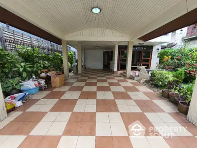 Spacious covered parking area with tiled flooring and lush greenery