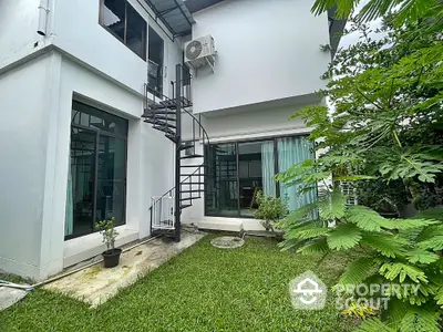 Charming modern home with spiral staircase and lush garden, perfect for tranquil living.