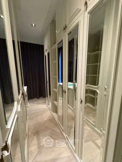 Luxurious walk-in closet with mirrored doors and elegant lighting