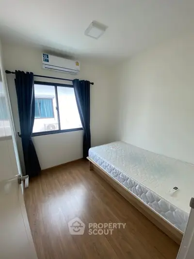 Cozy minimalist bedroom with single bed and window view, perfect for urban living.