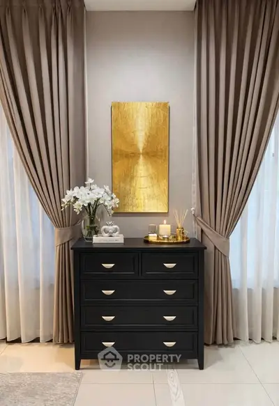 Elegant interior with black dresser, gold artwork, and luxurious curtains in a modern living space.