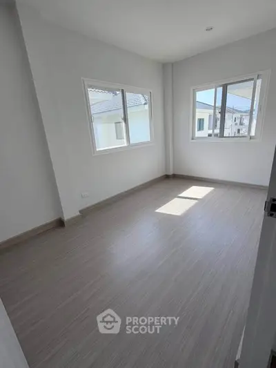 Bright empty room with large windows and modern flooring in a new residential property.