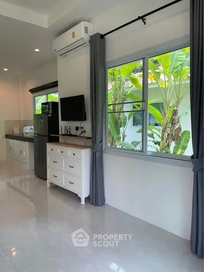 Bright living room with modern decor and large window overlooking lush greenery.