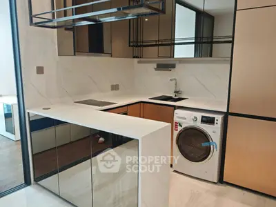 Modern kitchen with sleek design and built-in washing machine, featuring elegant cabinetry and marble countertops.