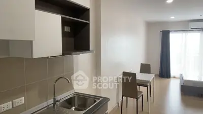 Modern studio apartment with open kitchen and dining area, featuring sleek cabinetry and natural light.