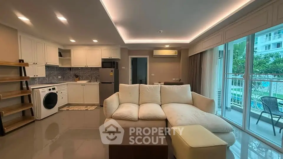 Spacious modern living room with open kitchen and balcony view in luxury apartment.