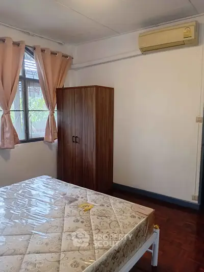 Cozy bedroom with wooden wardrobe and air conditioning, perfect for comfortable living.