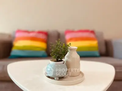 Cozy living room with colorful pillows and stylish decor on a white coffee table.