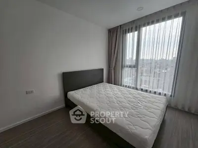 Modern bedroom with large window offering city view, featuring a minimalist design and comfortable bed.