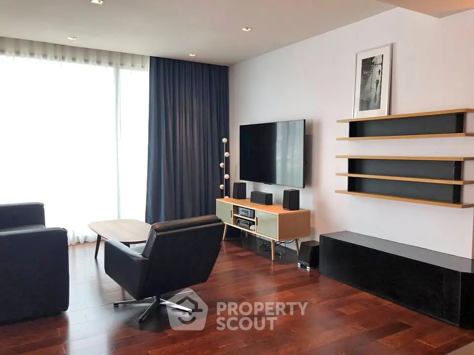 Modern living room with sleek furniture and large window, featuring hardwood floors and minimalist decor.