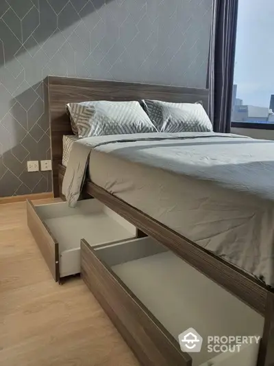 Modern bedroom with stylish bed and storage drawers, featuring a city view from the window.