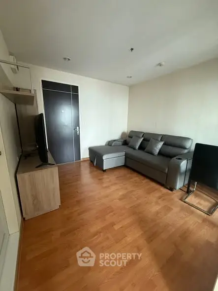 Modern living room with sleek gray sofa and wooden flooring, perfect for cozy relaxation.