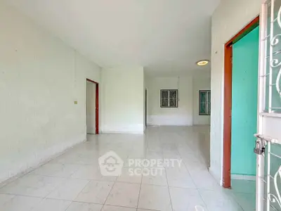 Spacious empty room with tiled flooring and multiple doorways in a bright home.