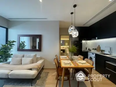 Chic modern apartment with an open layout connecting a cozy living area to a sleek kitchen, accentuated by stylish lighting and decor.