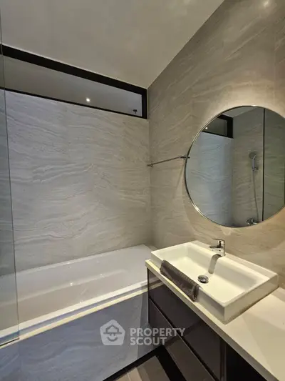 Modern bathroom with sleek design featuring a bathtub and round mirror, perfect for relaxation and style.