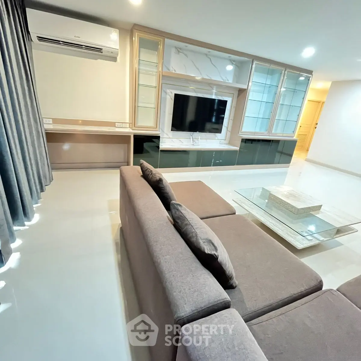 Spacious modern living room with sleek furniture and large TV, perfect for relaxation and entertainment.