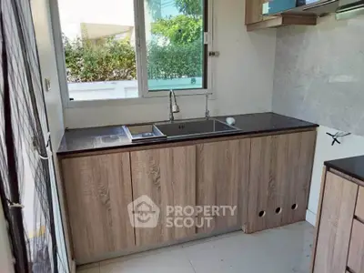 Modern kitchen with sleek wooden cabinets and large window view.