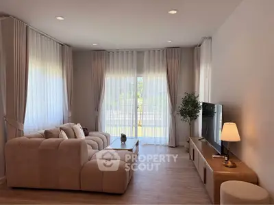 Elegant living room with plush sofa, large windows, and modern decor in a bright, inviting space.