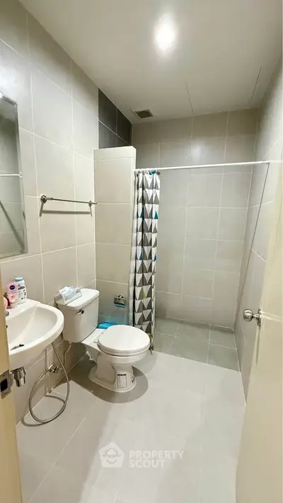 Modern bathroom with shower curtain and sleek fixtures in a neutral color palette.