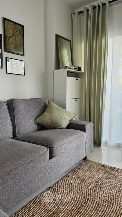Cozy living room with modern gray sofa, stylish decor, and natural light through sheer curtains.