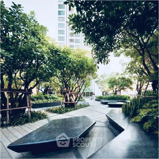 Lush garden area with modern seating in a residential complex, offering a serene outdoor retreat.
