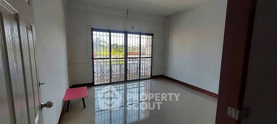 Spacious empty room with large window and balcony view, perfect for customization.