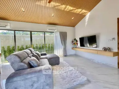 Spacious modern living room with plush seating and large TV, featuring elegant decor and natural light.