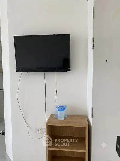 Minimalist interior with wall-mounted TV and wooden shelf in modern apartment.