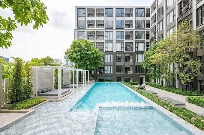 Modern apartment complex with luxurious outdoor pool and lush greenery.
