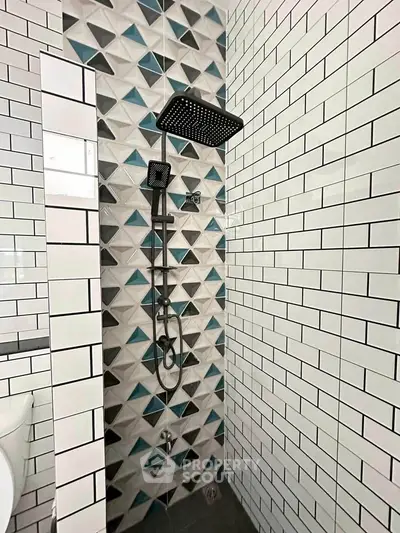 Modern bathroom with geometric tile design and sleek black shower fixtures.