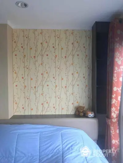 Cozy bedroom with floral wallpaper and plush toys on the shelf, perfect for relaxation.