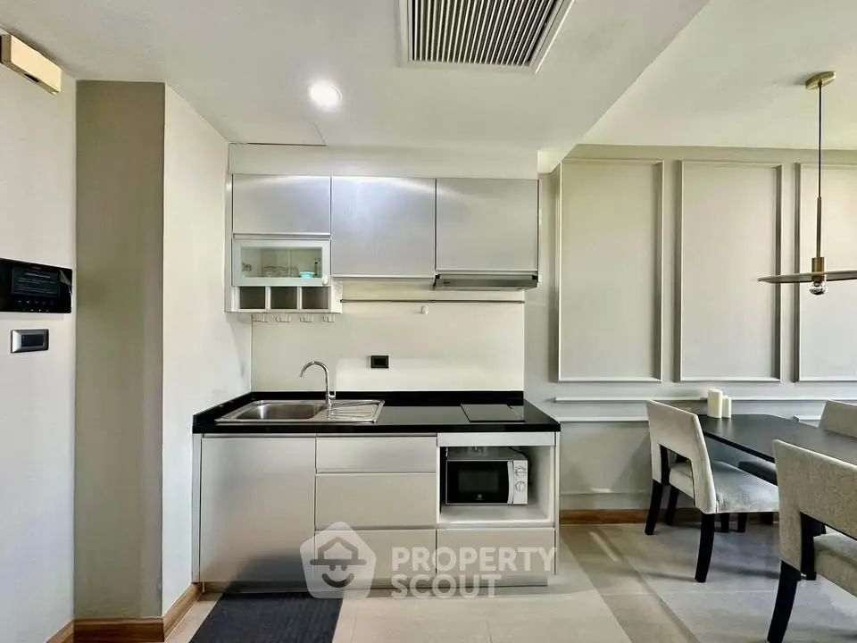 Modern kitchen with sleek cabinetry and dining area in stylish apartment