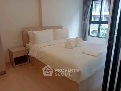 Cozy bedroom with elegant decor and large window offering natural light in modern apartment.