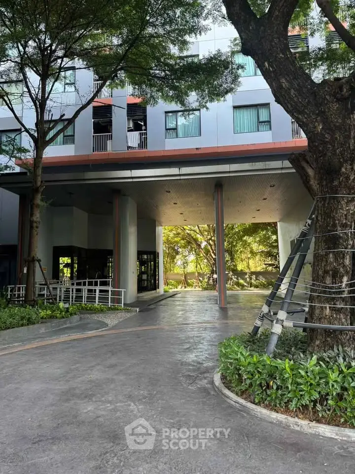 Modern building entrance with lush greenery and spacious driveway