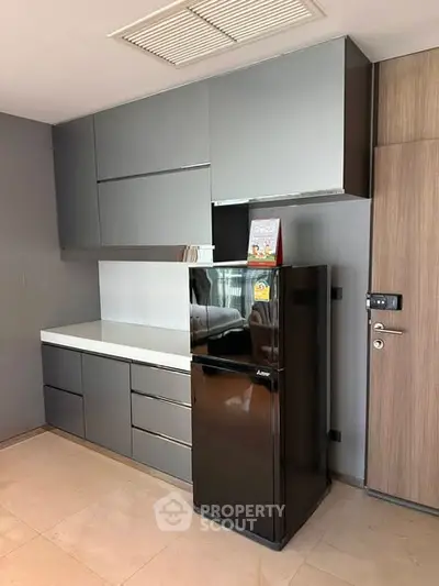 Modern kitchen with sleek cabinetry and compact refrigerator in a stylish apartment.
