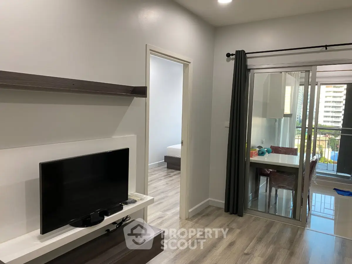 Modern apartment interior with sleek living room and balcony view, featuring contemporary furniture and open layout.